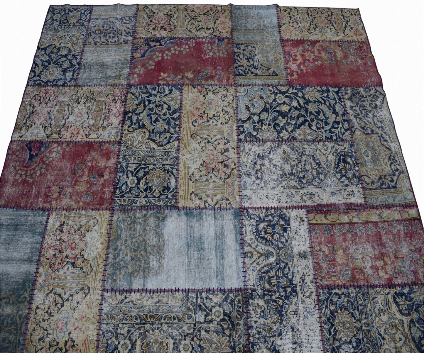 A handmade vintage patchwork rug featuring a variety of floral and ornate patterns in red and blue.