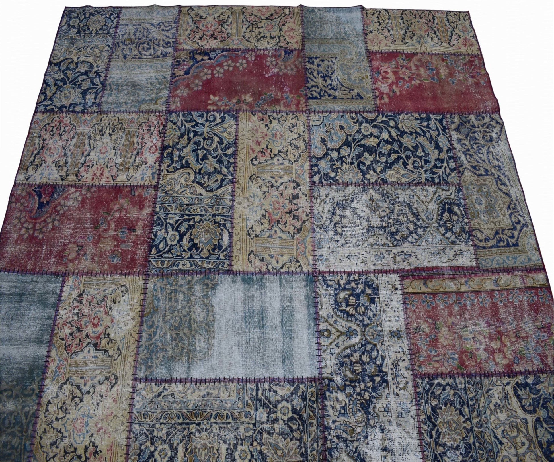 A handmade vintage patchwork rug featuring a variety of floral and ornate patterns in red and blue.