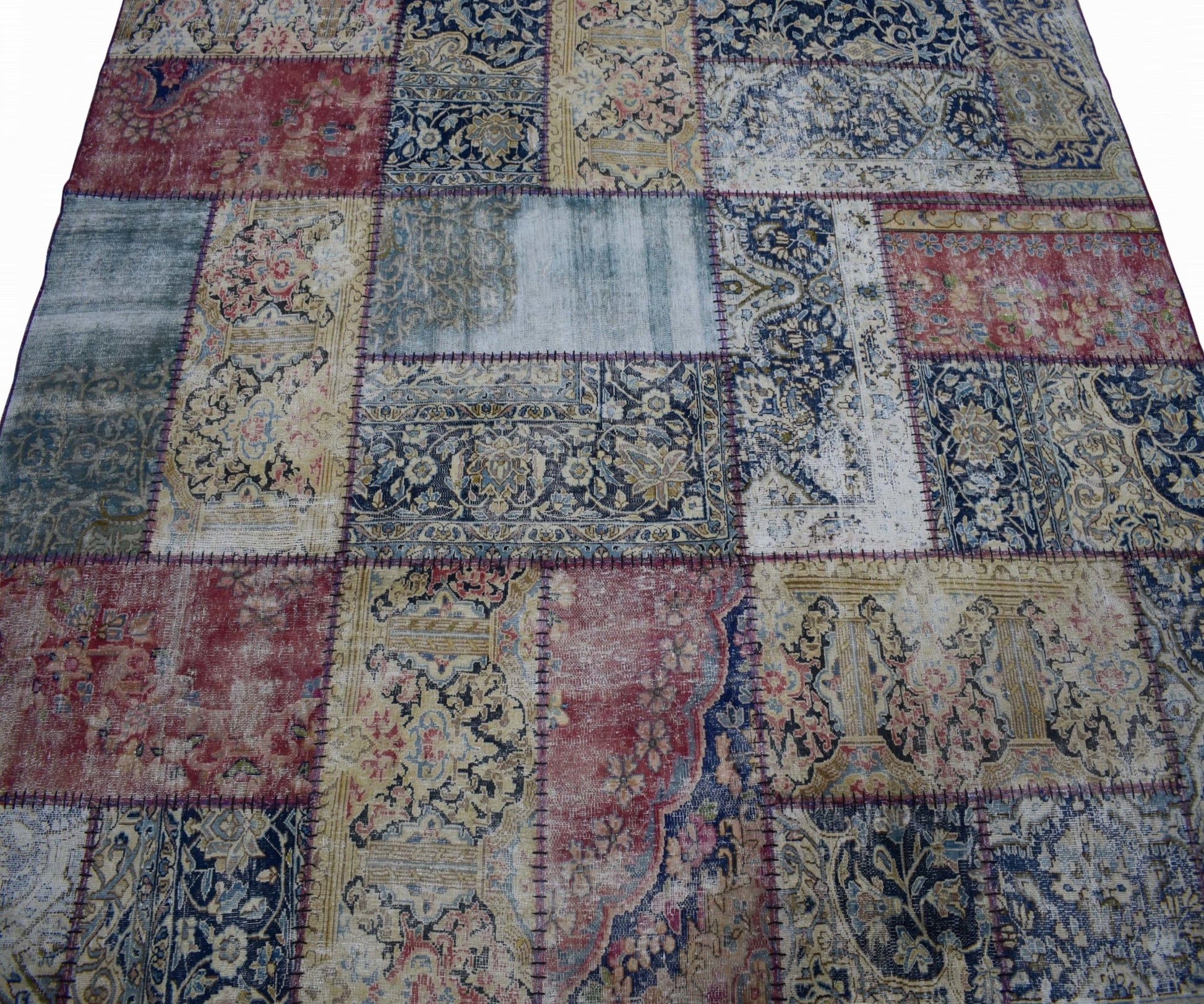 A handmade vintage patchwork rug featuring a variety of ornate floral patterns in red and blue.