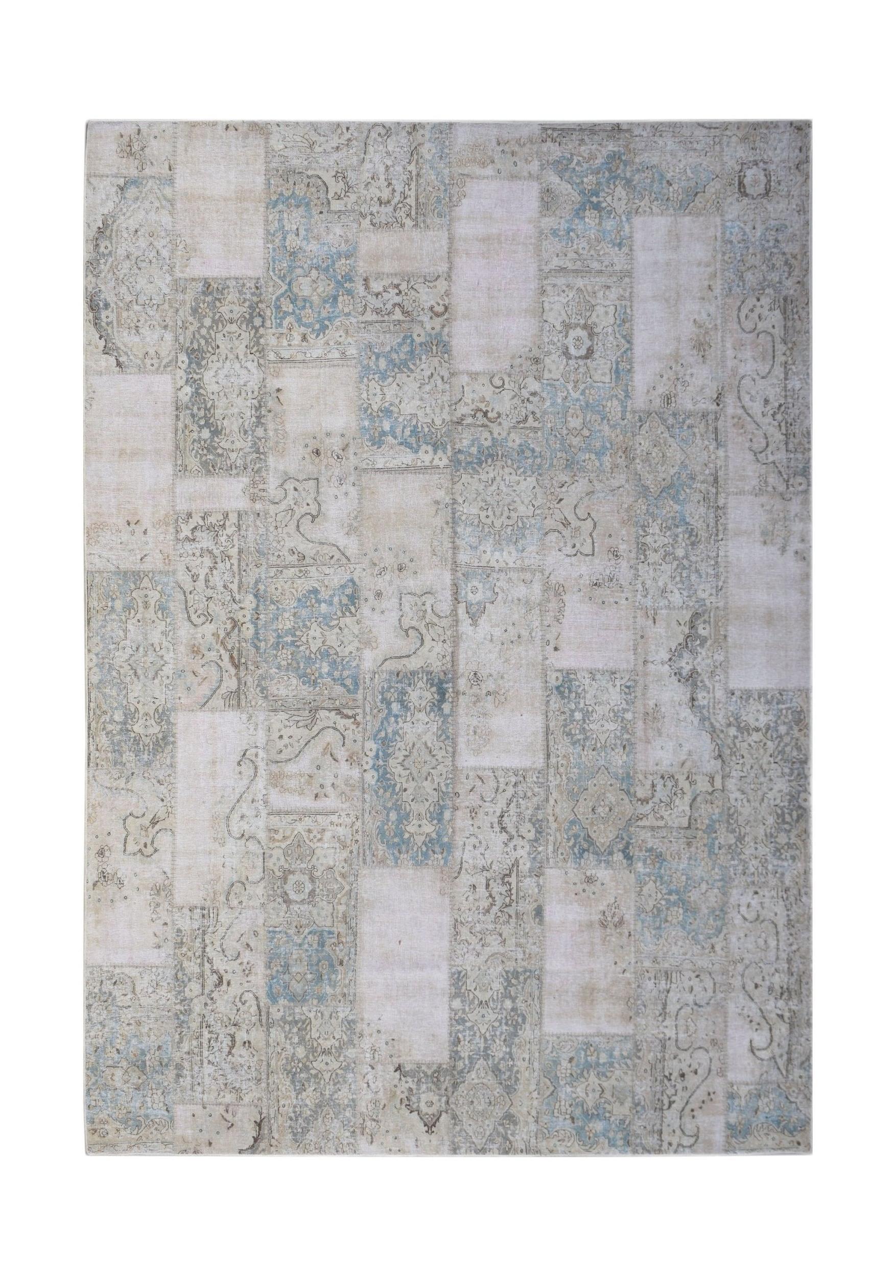 A handmade vintage patchwork rug featuring a faded blue and beige traditional pattern.