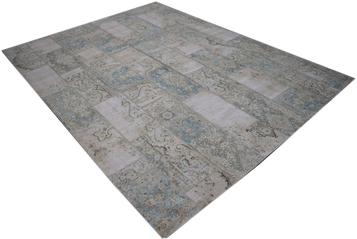 A rectangular handmade patchwork rug featuring a faded vintage design in shades of blue and beige.