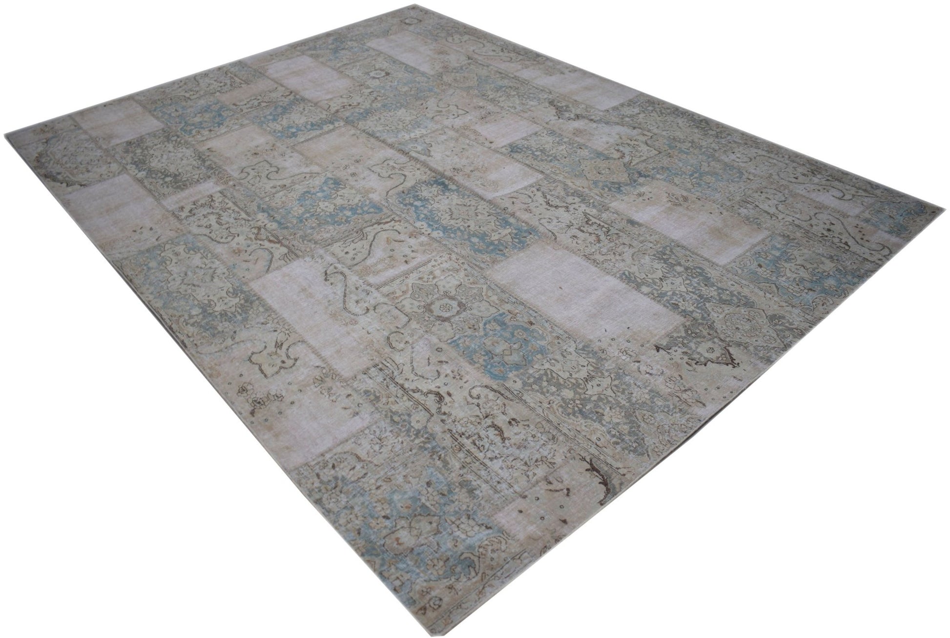 A rectangular handmade patchwork rug featuring a faded vintage design in shades of blue and beige.