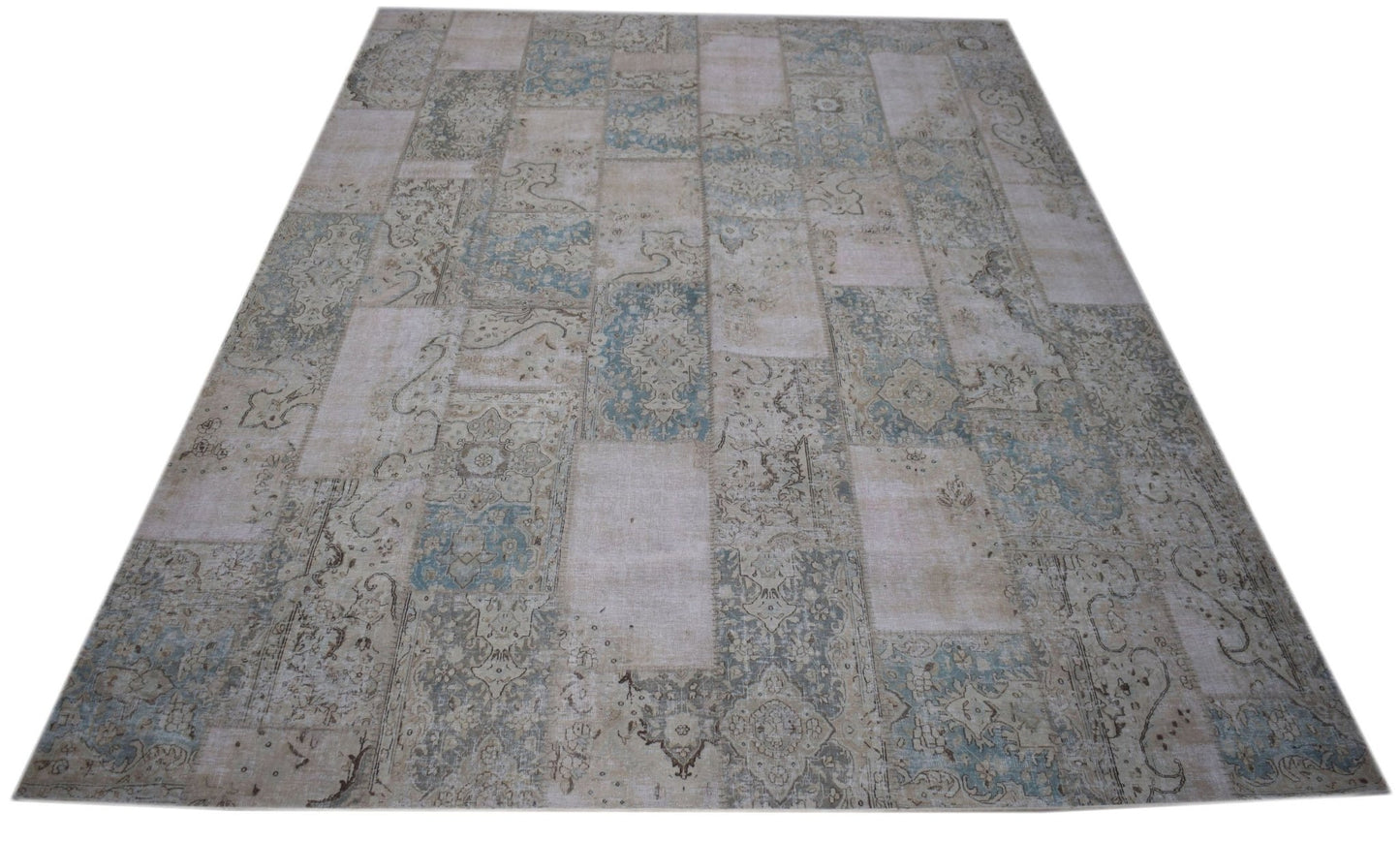 A handmade vintage patchwork rug featuring a faded blue and beige floral pattern.