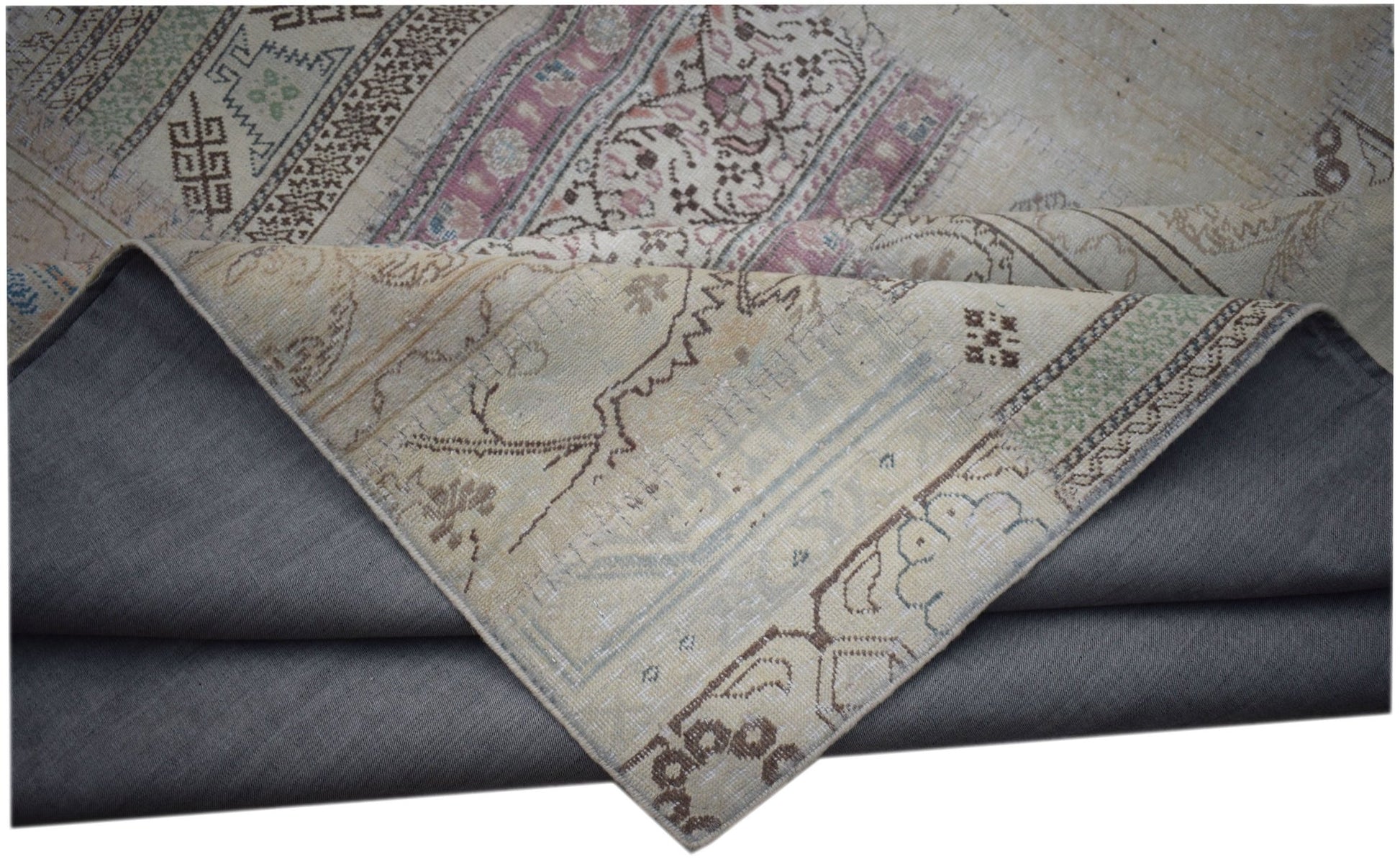 A vintage patchwork rug with a folded corner revealing its intricate floral and geometric patterns.