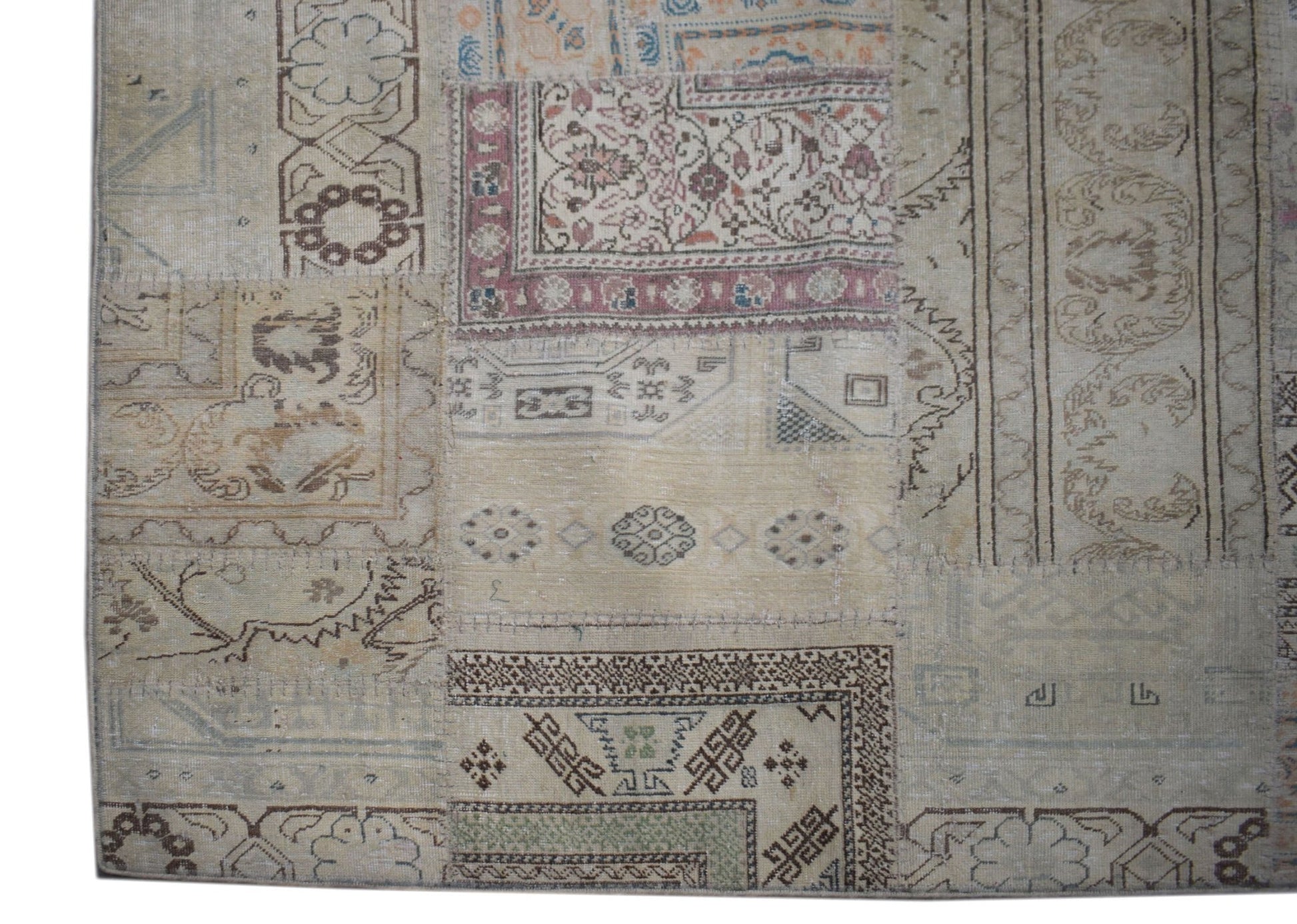 A handmade vintage patchwork rug featuring a neutral color palette and diverse geometric patterns.