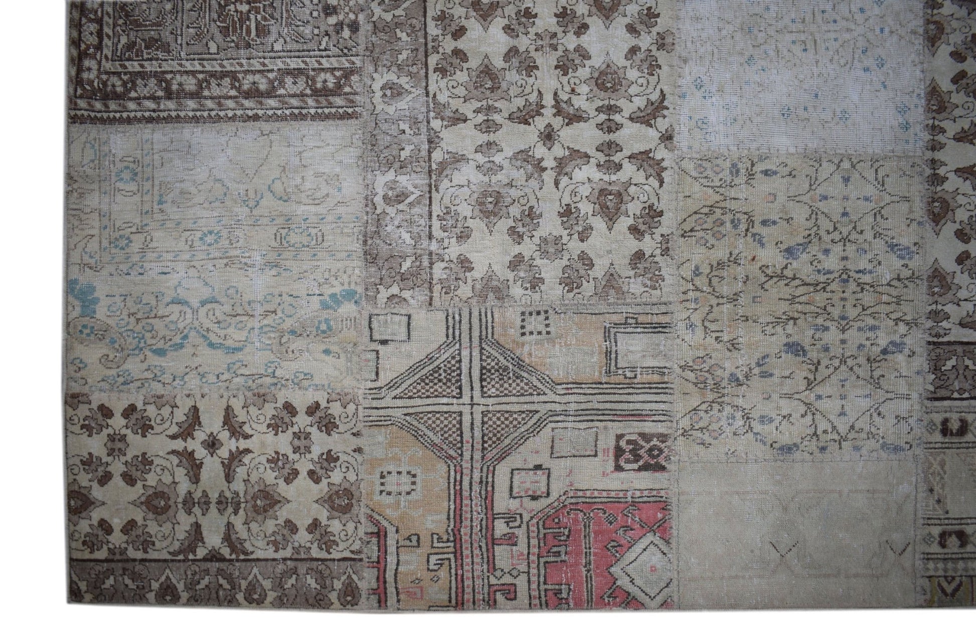 A handmade vintage patchwork rug featuring a variety of neutral-toned floral and geometric patterns.