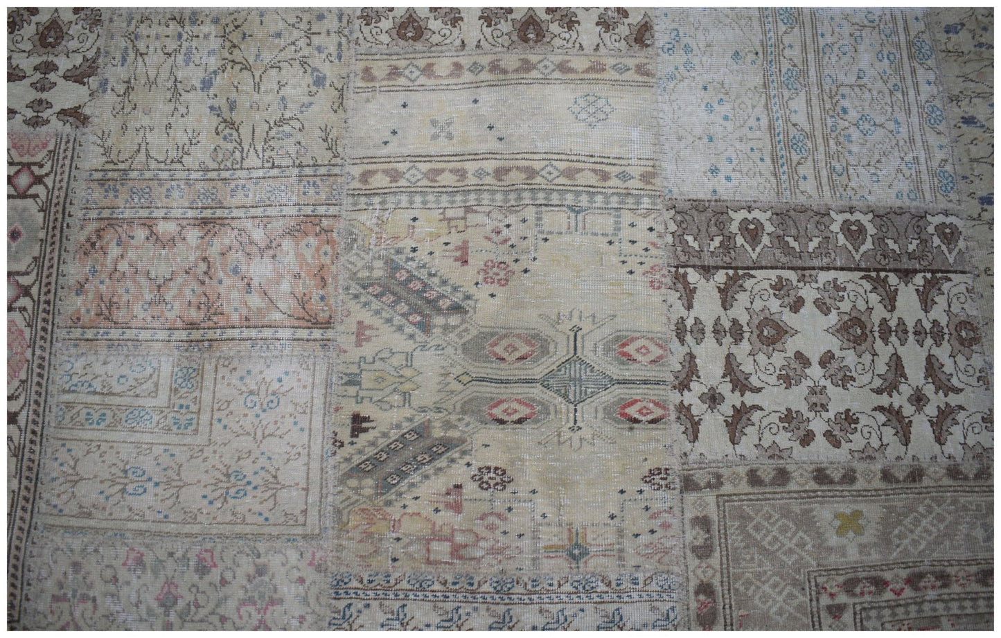 A handmade vintage patchwork rug featuring a variety of faded floral and geometric patterns.