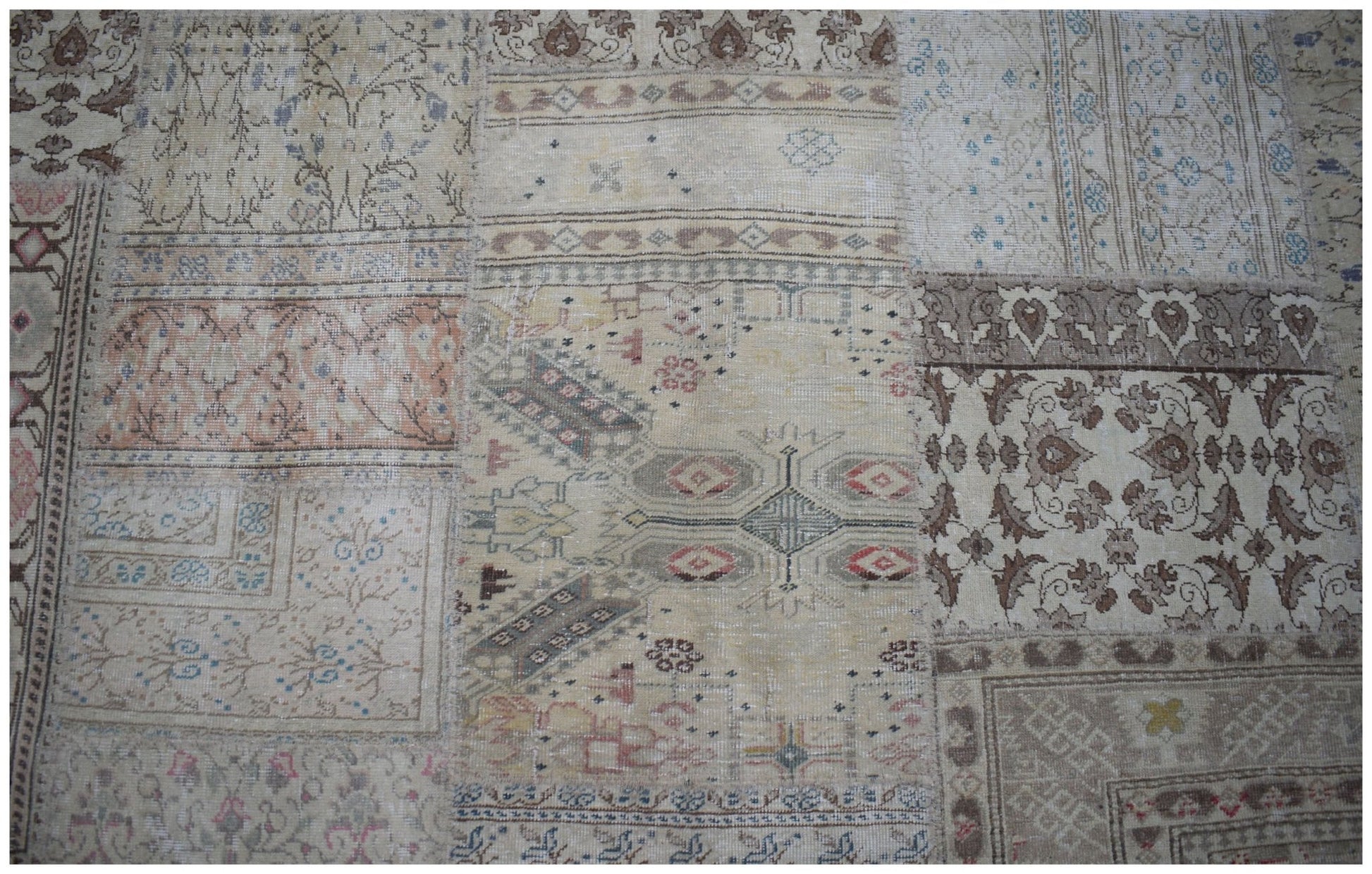 A handmade vintage patchwork rug featuring a variety of faded floral and geometric patterns.