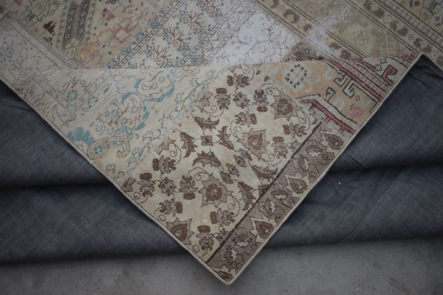 A vintage patchwork rug with floral and geometric patterns in muted earth tones.