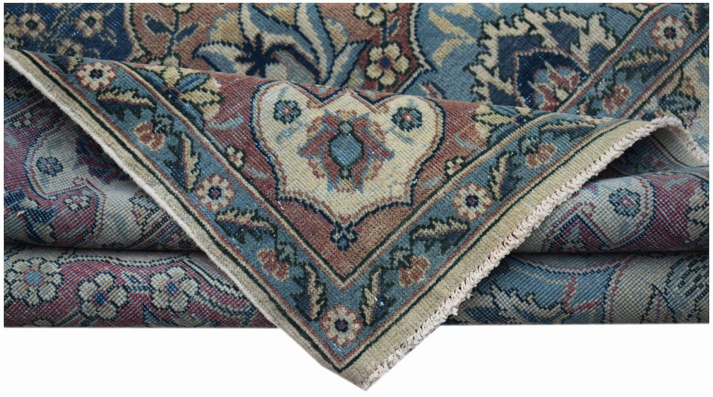 A folded vintage Persian Bakhtiari rug featuring intricate floral patterns in blue and red tones.