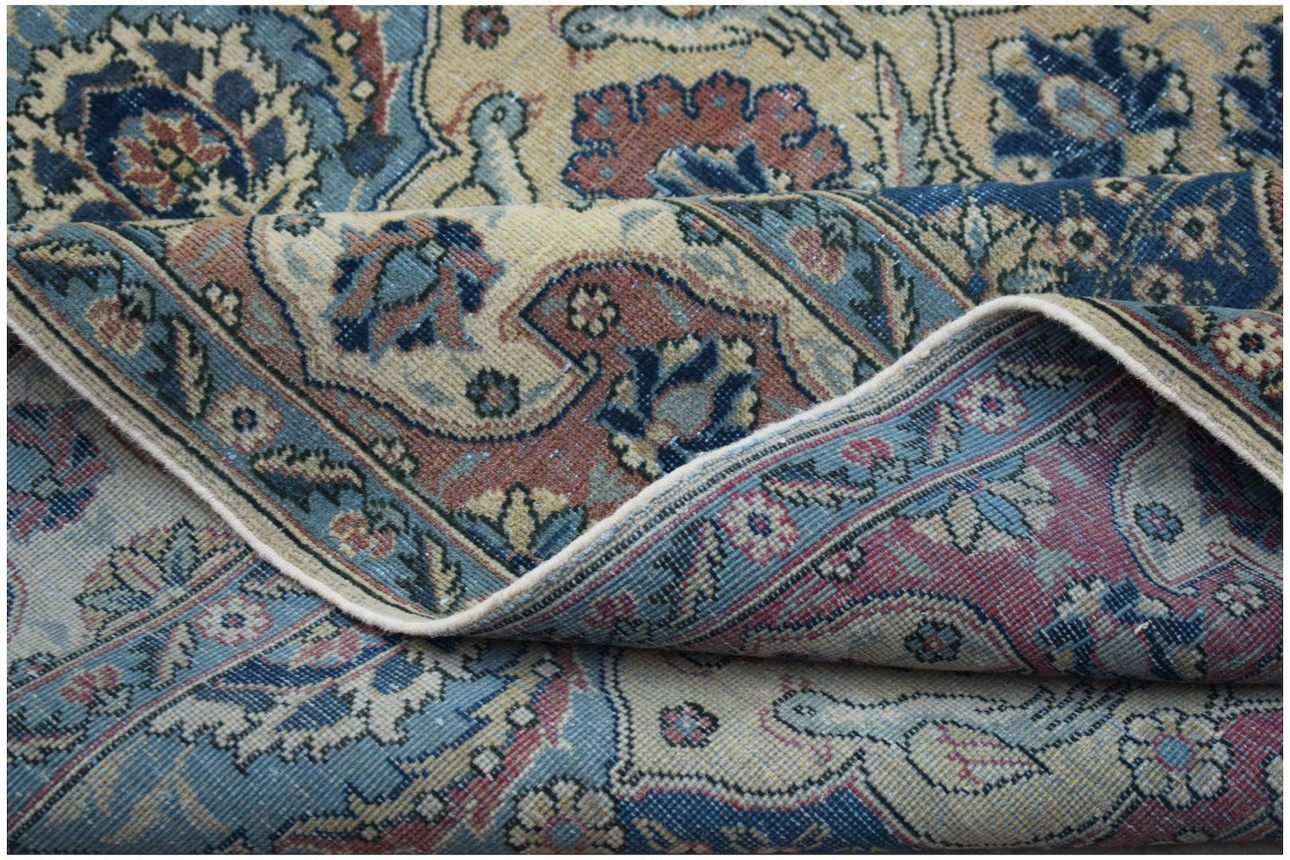 A vintage Persian Bakhtiari rug featuring intricate floral patterns in blue, red, and beige tones.