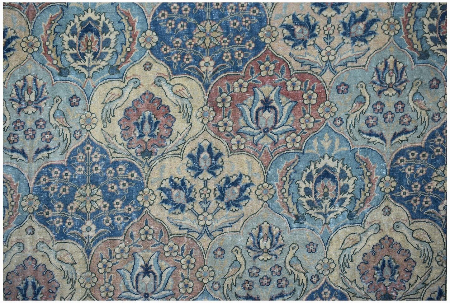 A vintage Persian Bakhtiari rug featuring a repeating floral and bird pattern in blue and red tones.
