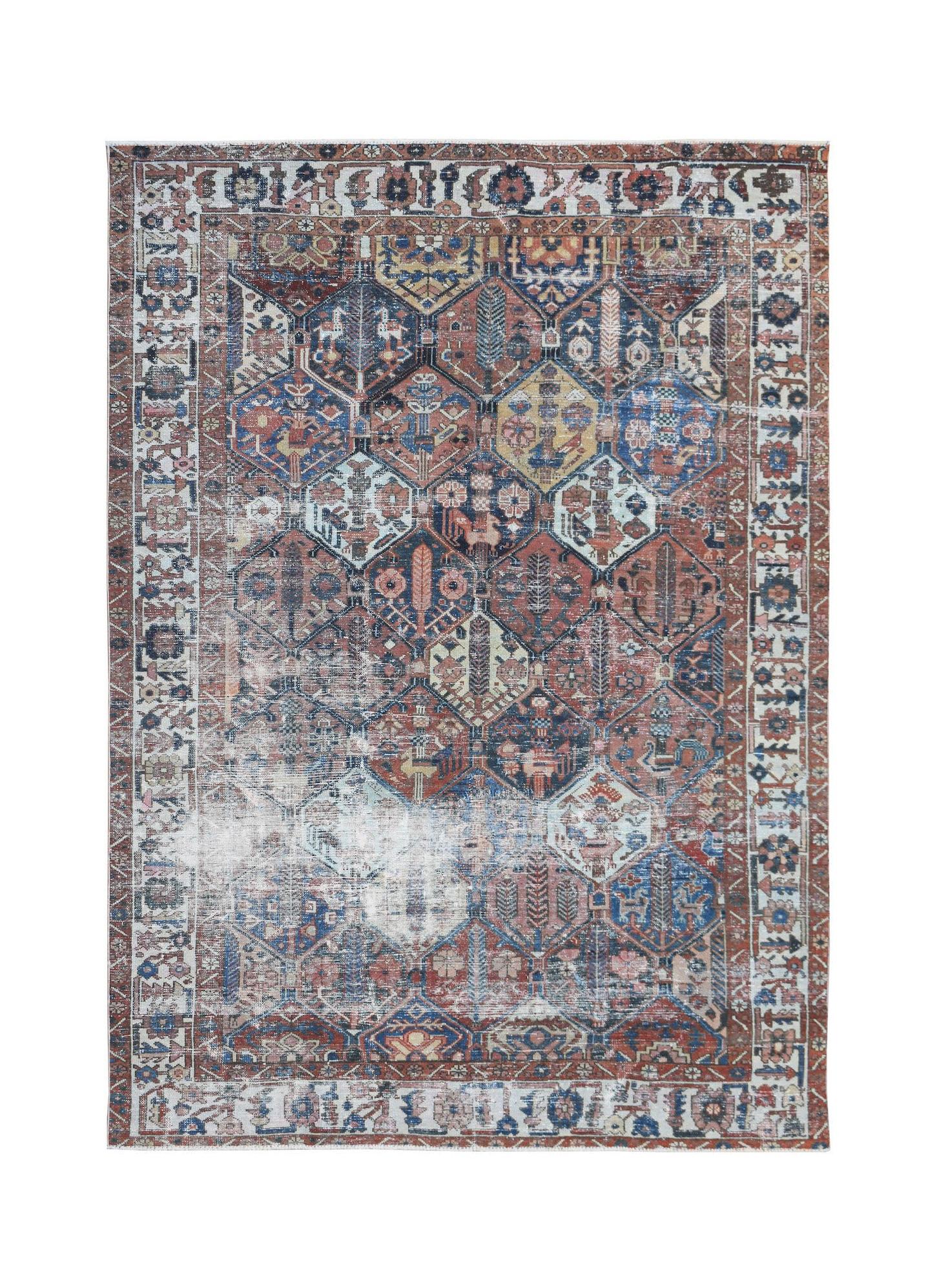 A vintage Persian Bakhtiari rug featuring a distressed geometric garden pattern in muted tones.