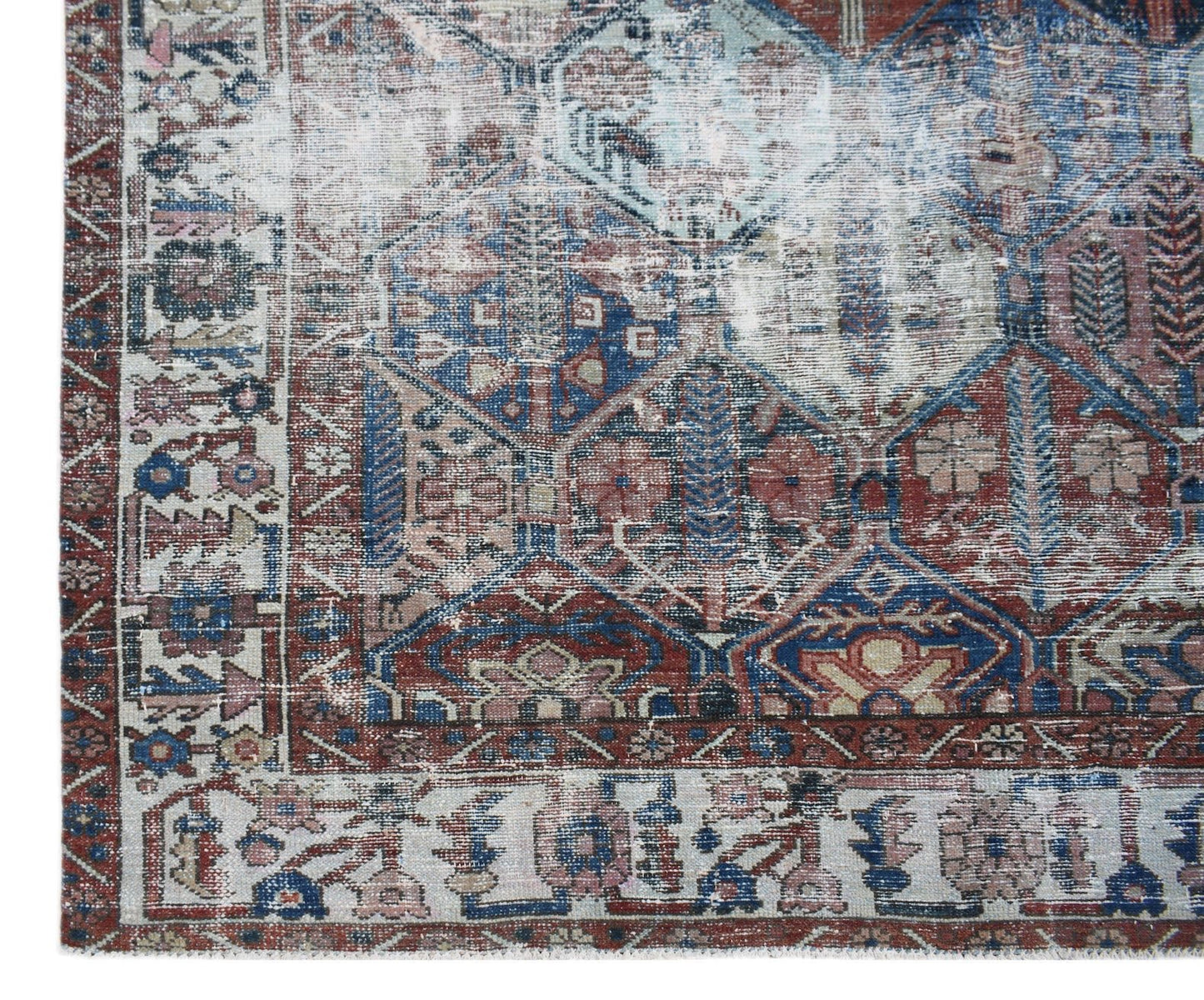 A vintage handwoven Persian Bakhtiari rug featuring a distressed geometric pattern in blue and red.