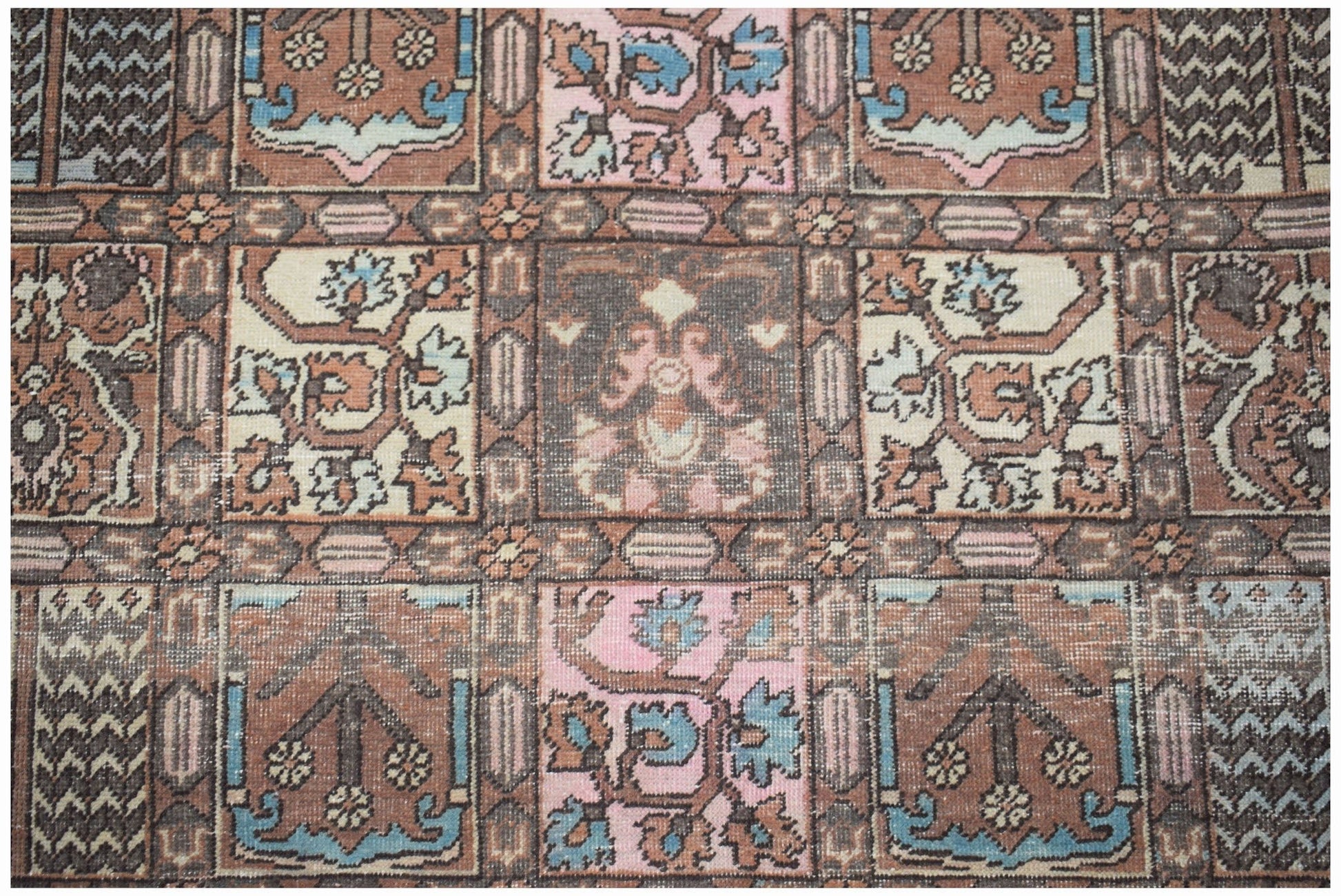 A vintage Persian Bakhtiari rug featuring a geometric grid pattern in muted earth tones and blue.