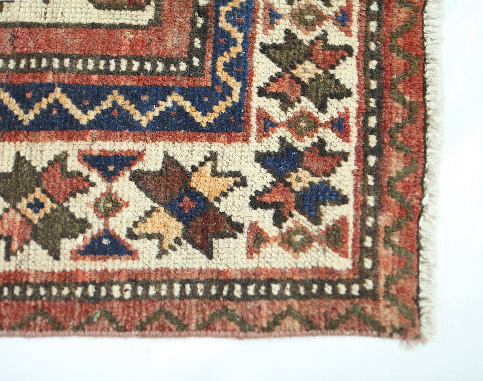 A corner view of a vintage Persian Bakhtiari rug featuring intricate geometric floral patterns.