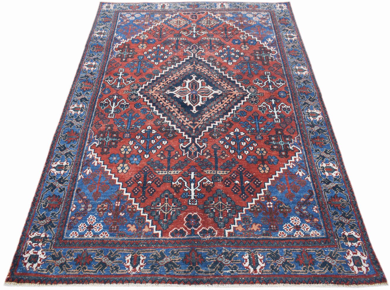 A vintage handwoven Persian Ghashghai rug featuring a geometric diamond pattern in red and blue.