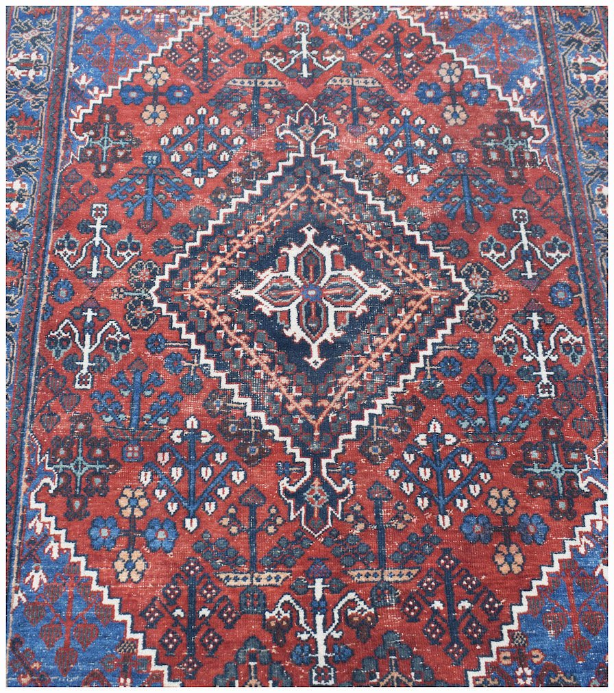 Vintage Persian Ghashghai rug featuring a central diamond medallion on a red field.