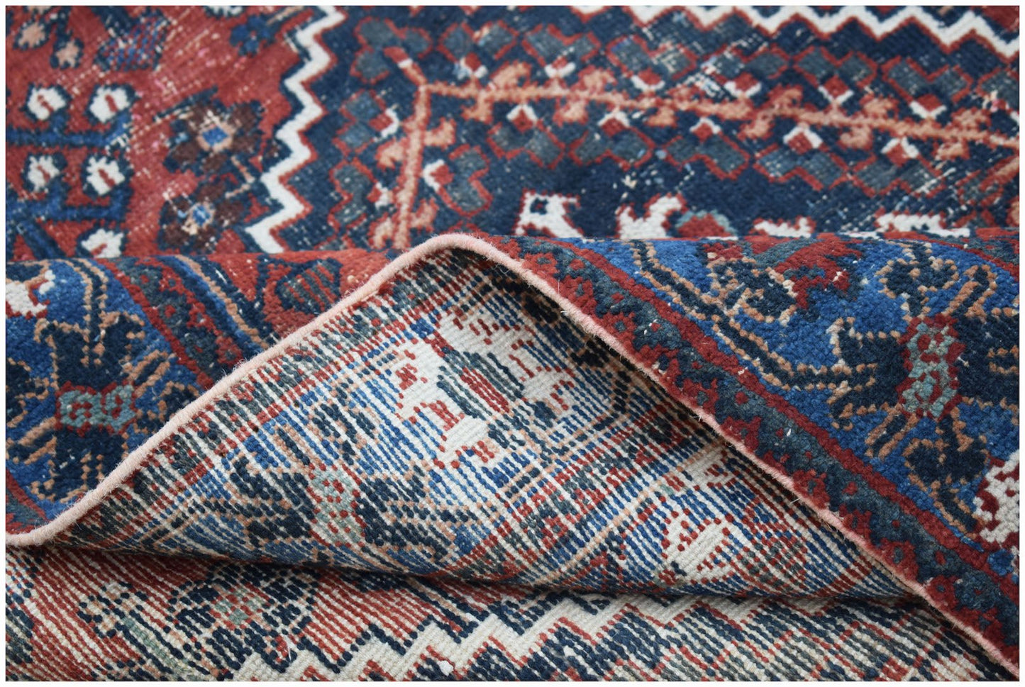 A handwoven vintage Persian Ghashghai rug featuring intricate geometric patterns in red and blue.