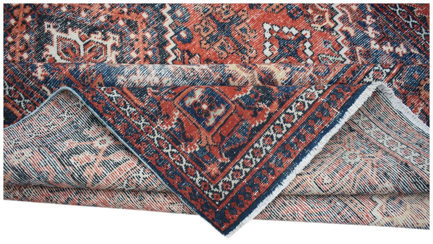 A vintage handwoven Persian Ghashghai rug featuring a geometric pattern in red and blue tones.
