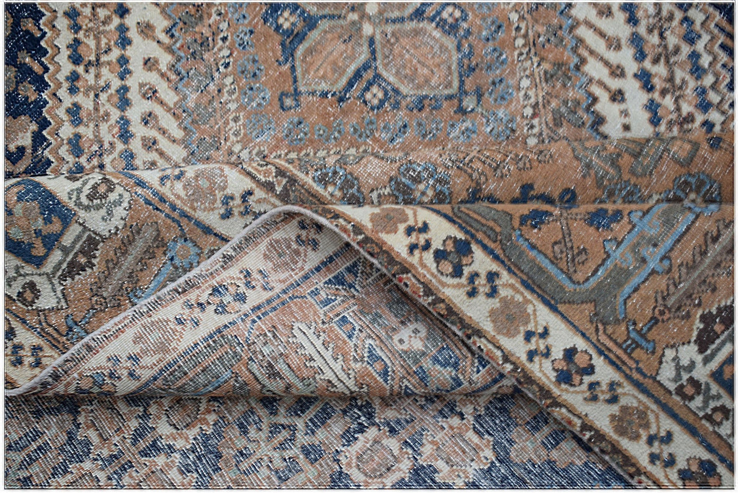 A vintage handwoven Persian Ghashghai rug featuring a distressed blue and tan geometric pattern.