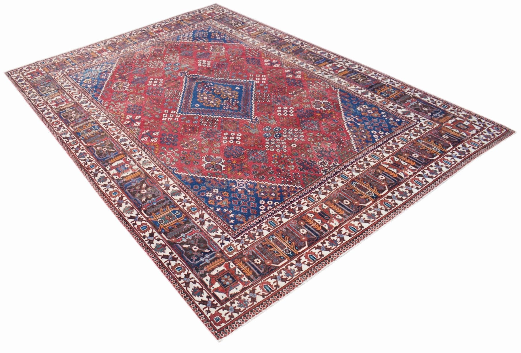 A vintage Persian Ghashghai rug featuring a red field with blue geometric medallions and borders.