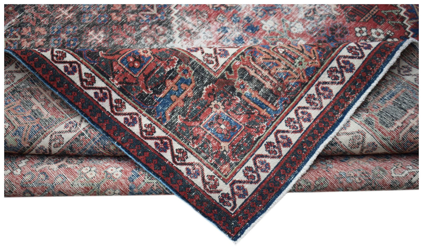 A vintage handwoven Persian Ghashghai rug featuring a distressed red and blue geometric pattern.