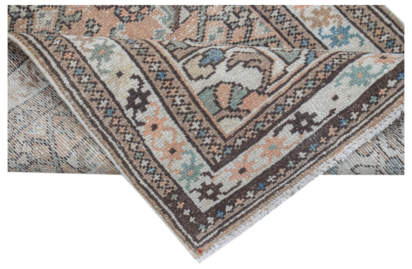 A handwoven vintage Persian runner featuring a geometric pattern in muted earth tones.