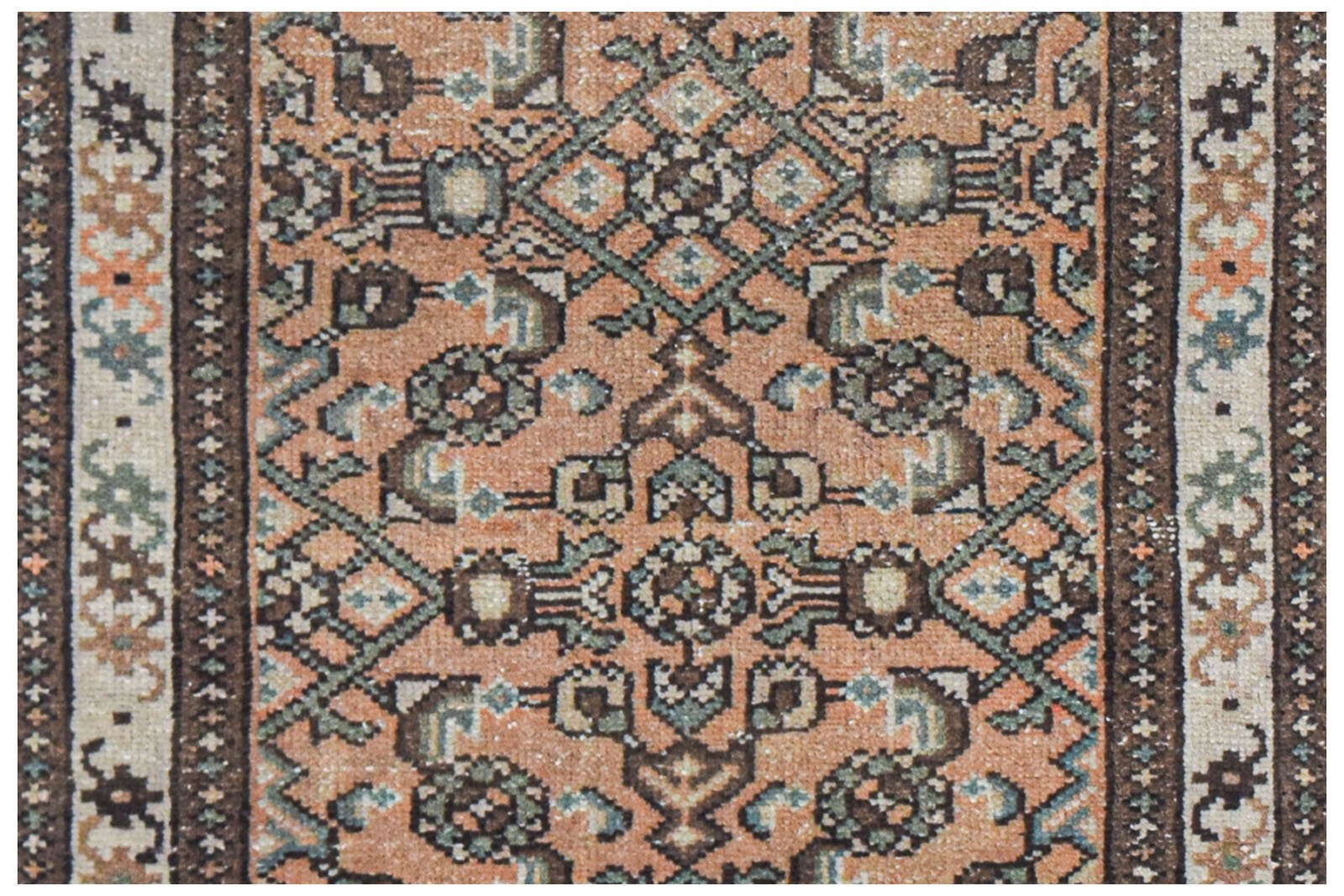 A vintage Persian runner featuring a geometric pattern in shades of orange, brown, and green.