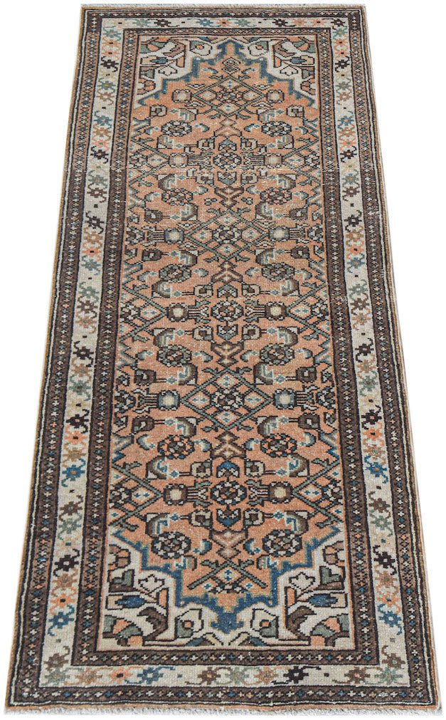 A handwoven vintage Persian runner featuring a geometric pattern in muted orange, blue, and brown.