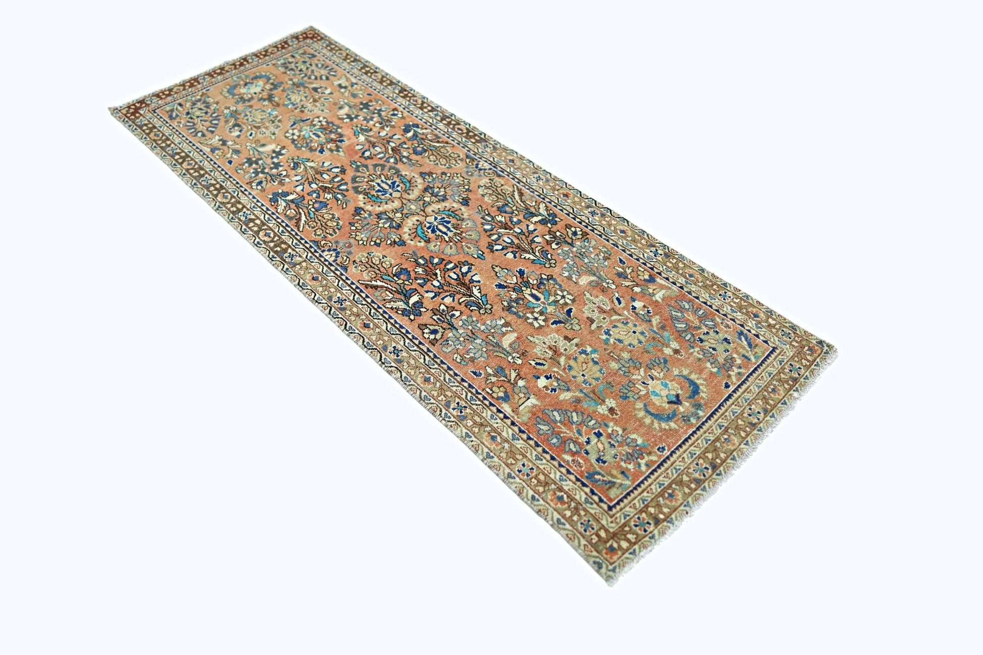 A vintage Persian runner rug featuring intricate floral patterns in blue and cream on a peach base.