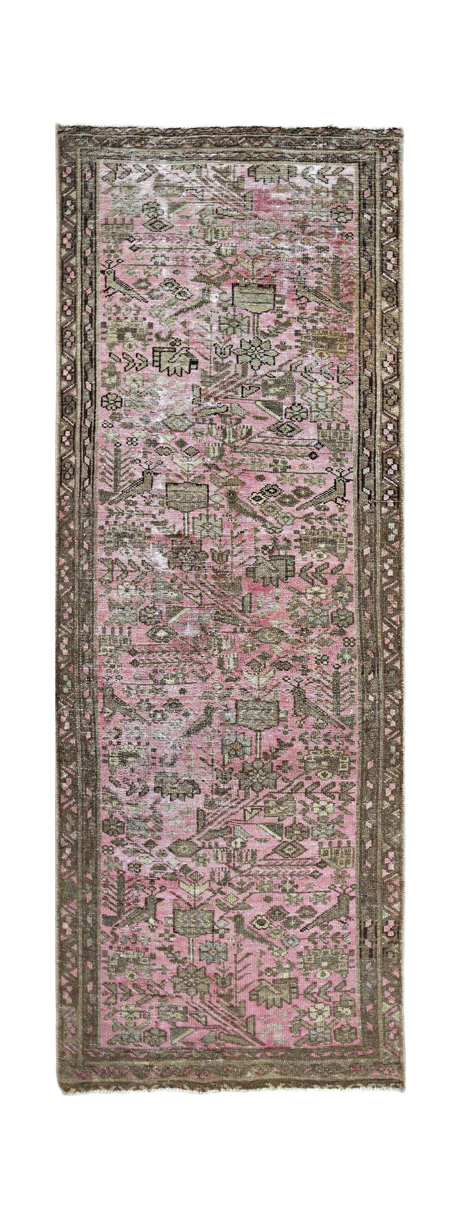 A vintage Persian runner rug featuring a faded pink field with intricate geometric floral motifs.