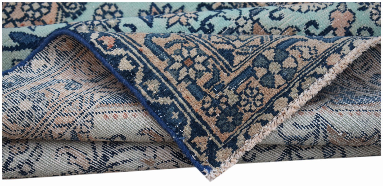 A folded vintage Persian runner featuring intricate blue and beige floral patterns.