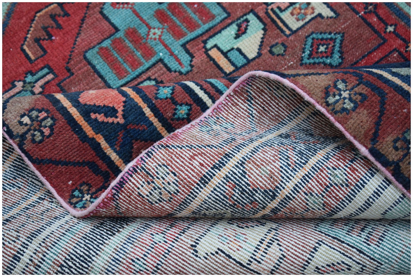 A handwoven vintage Persian runner featuring geometric patterns in red, blue, and cream wool.