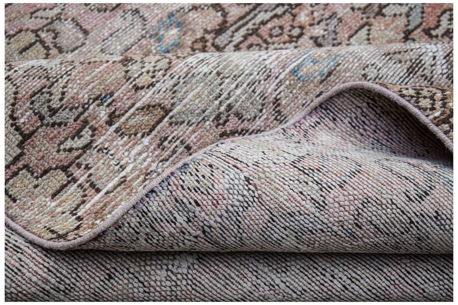 A folded vintage Persian Hamadan runner featuring a faded, intricate pattern in wool.