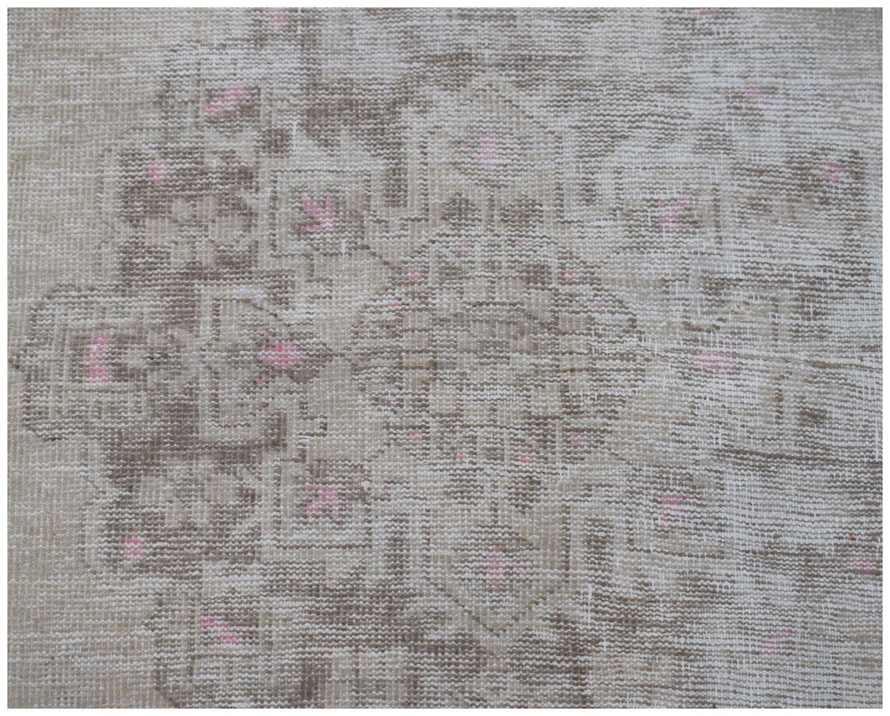 A vintage Persian runner featuring a faded geometric pattern in beige and brown with pink accents.