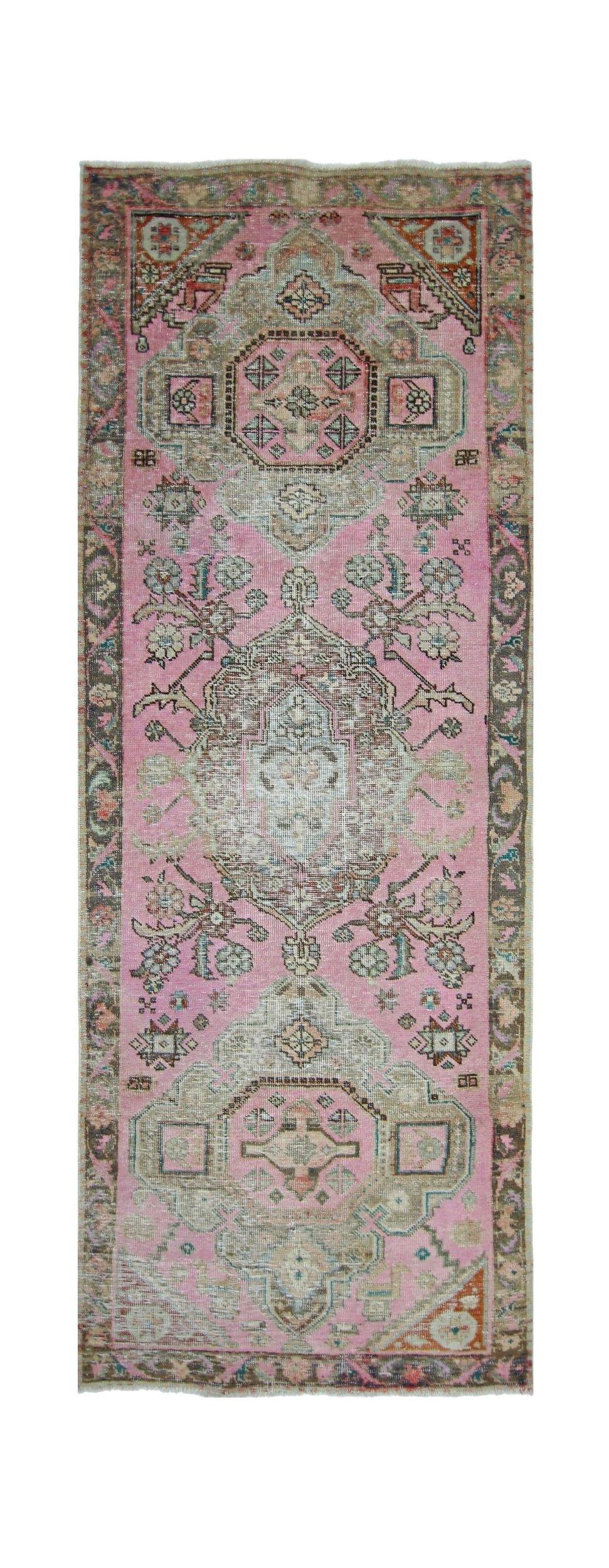 A vintage Persian runner rug featuring a pink field with intricate geometric and floral patterns.