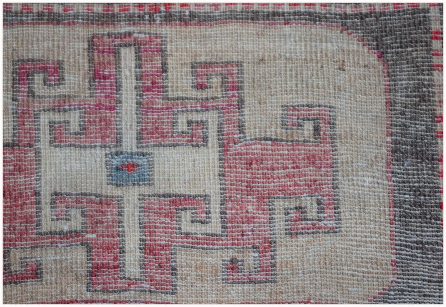 A close-up of a vintage Persian runner featuring a geometric pink and cream patterned design.
