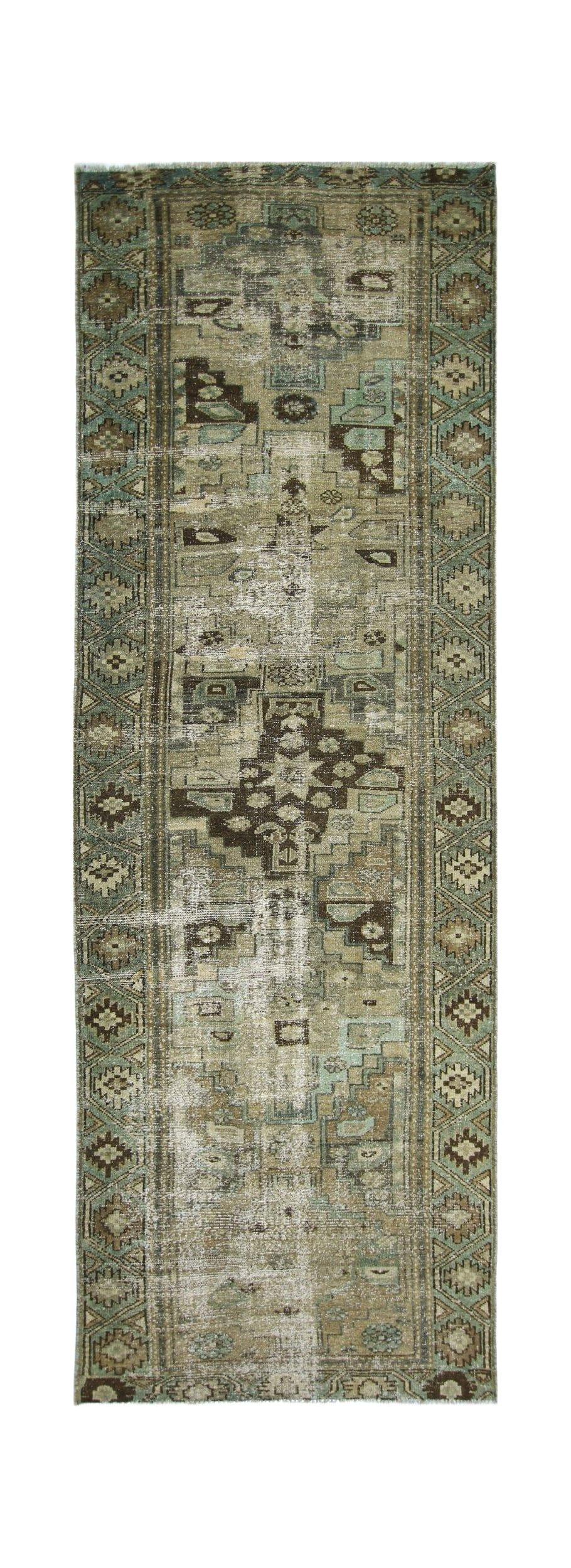 A vintage handmade Persian runner rug featuring a geometric pattern in muted green and brown tones.
