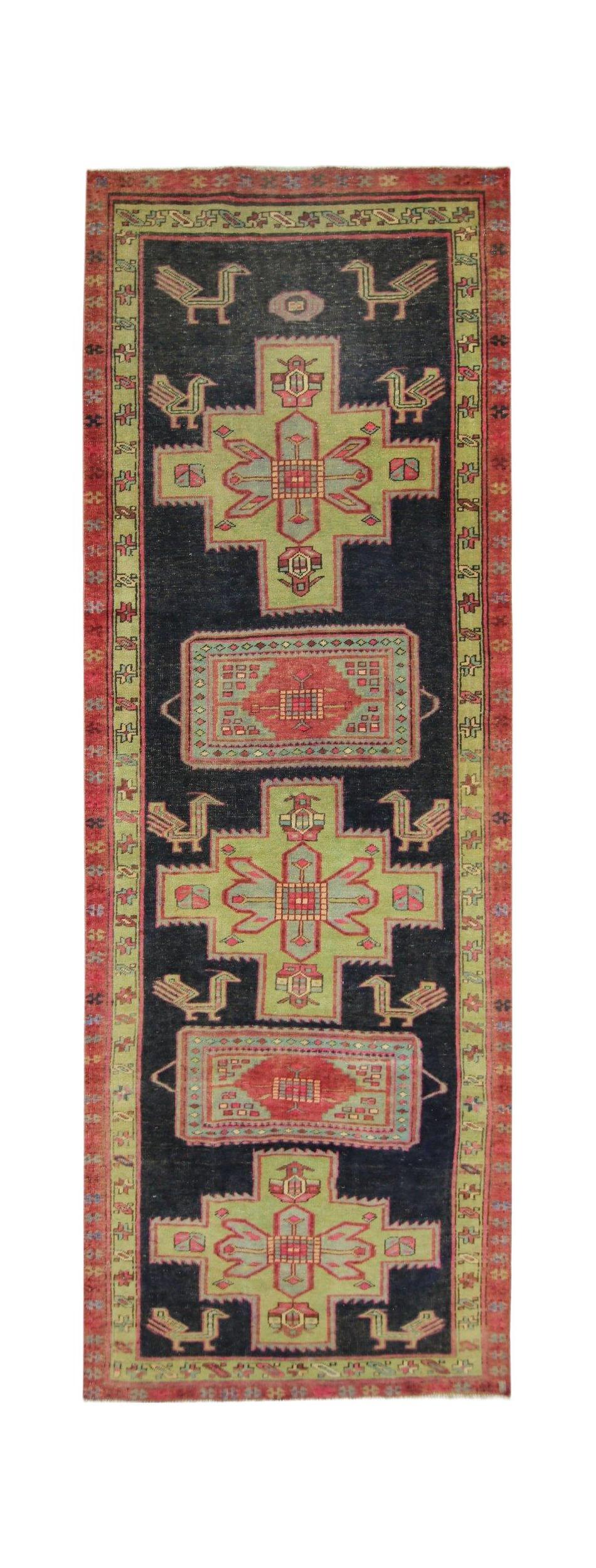A vintage Persian Ardabil runner featuring geometric green and red medallions on a black field.