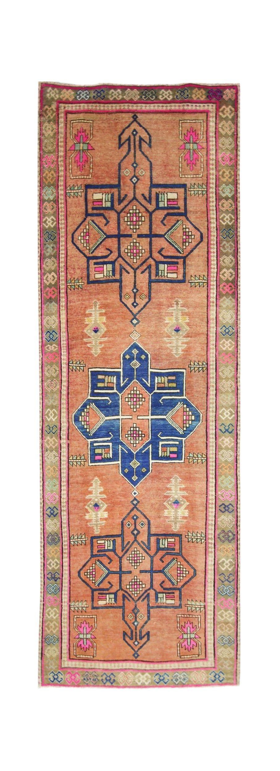 A handmade vintage Persian runner featuring geometric motifs in blue and pink on an orange field.
