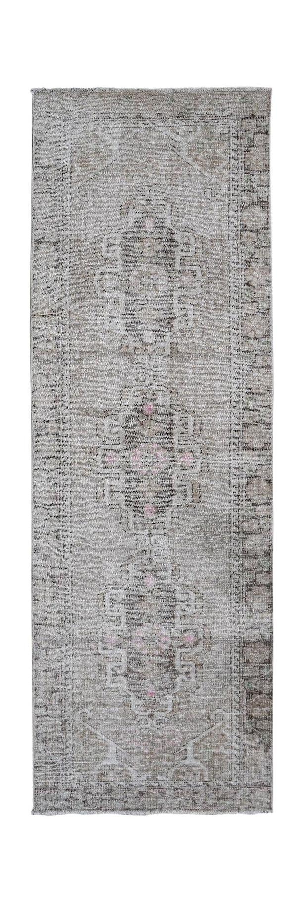 A vintage Persian runner rug featuring a faded grey and brown pattern with subtle pink accents.