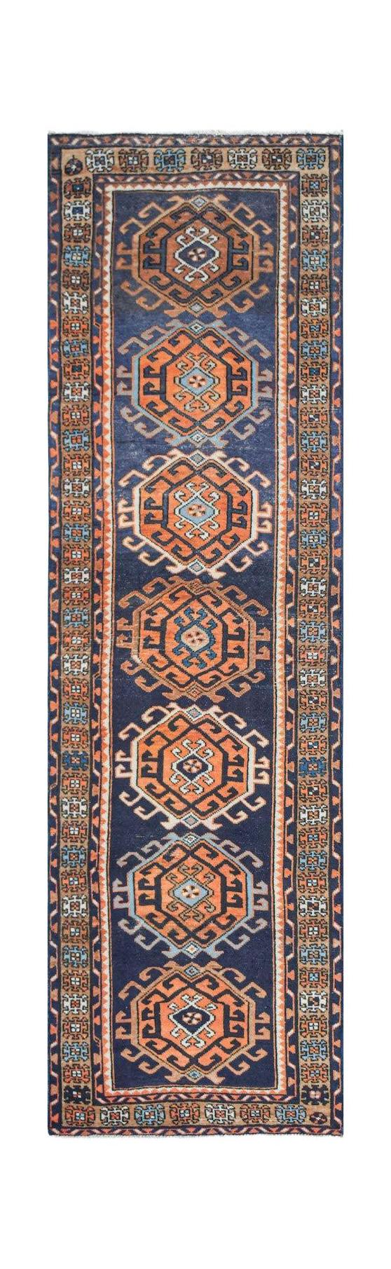 A handwoven vintage Persian runner featuring repeating orange octagonal medallions on a blue field.
