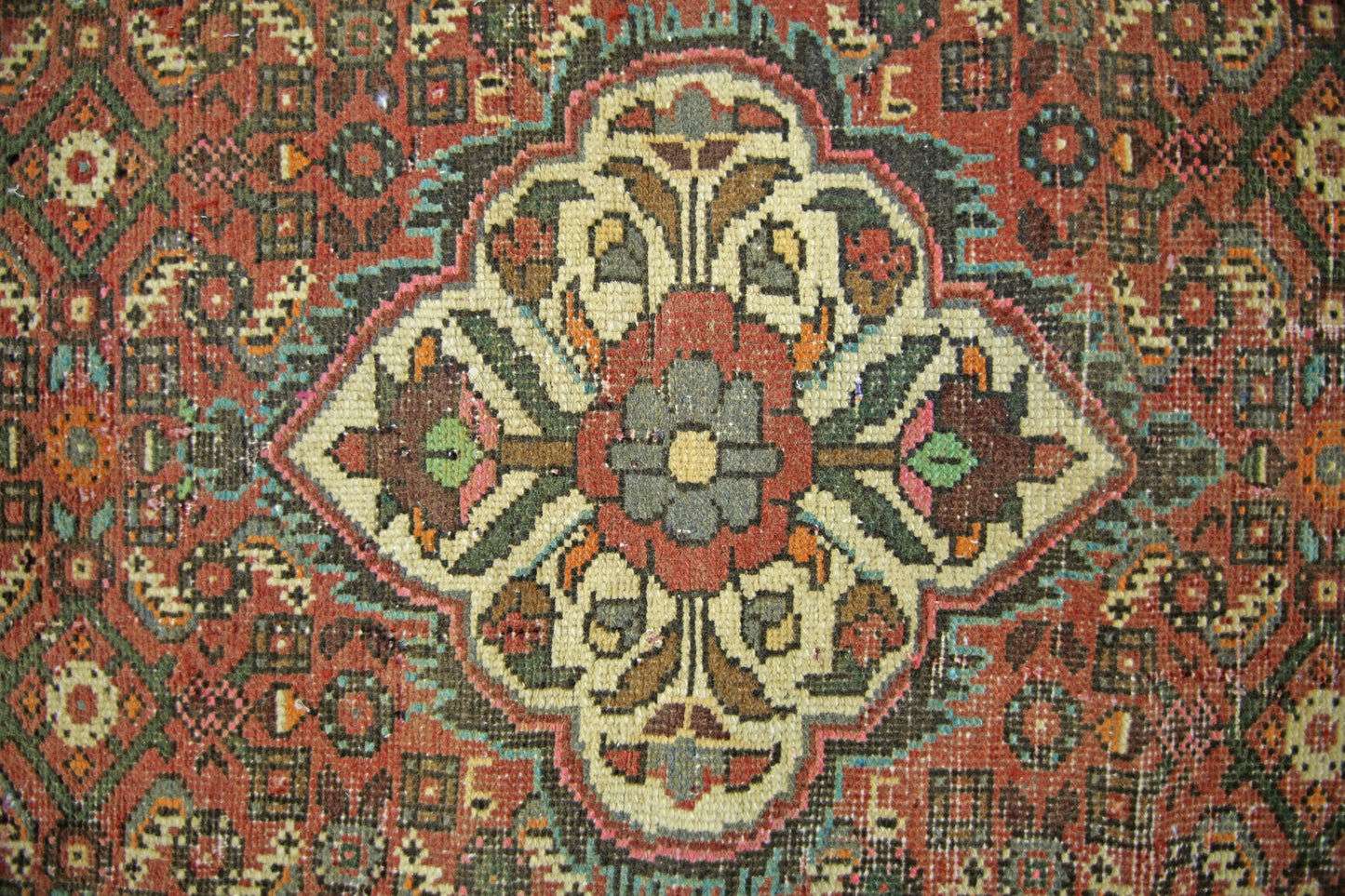A vintage Persian runner featuring a central floral medallion in a geometric, multi-colored pattern.