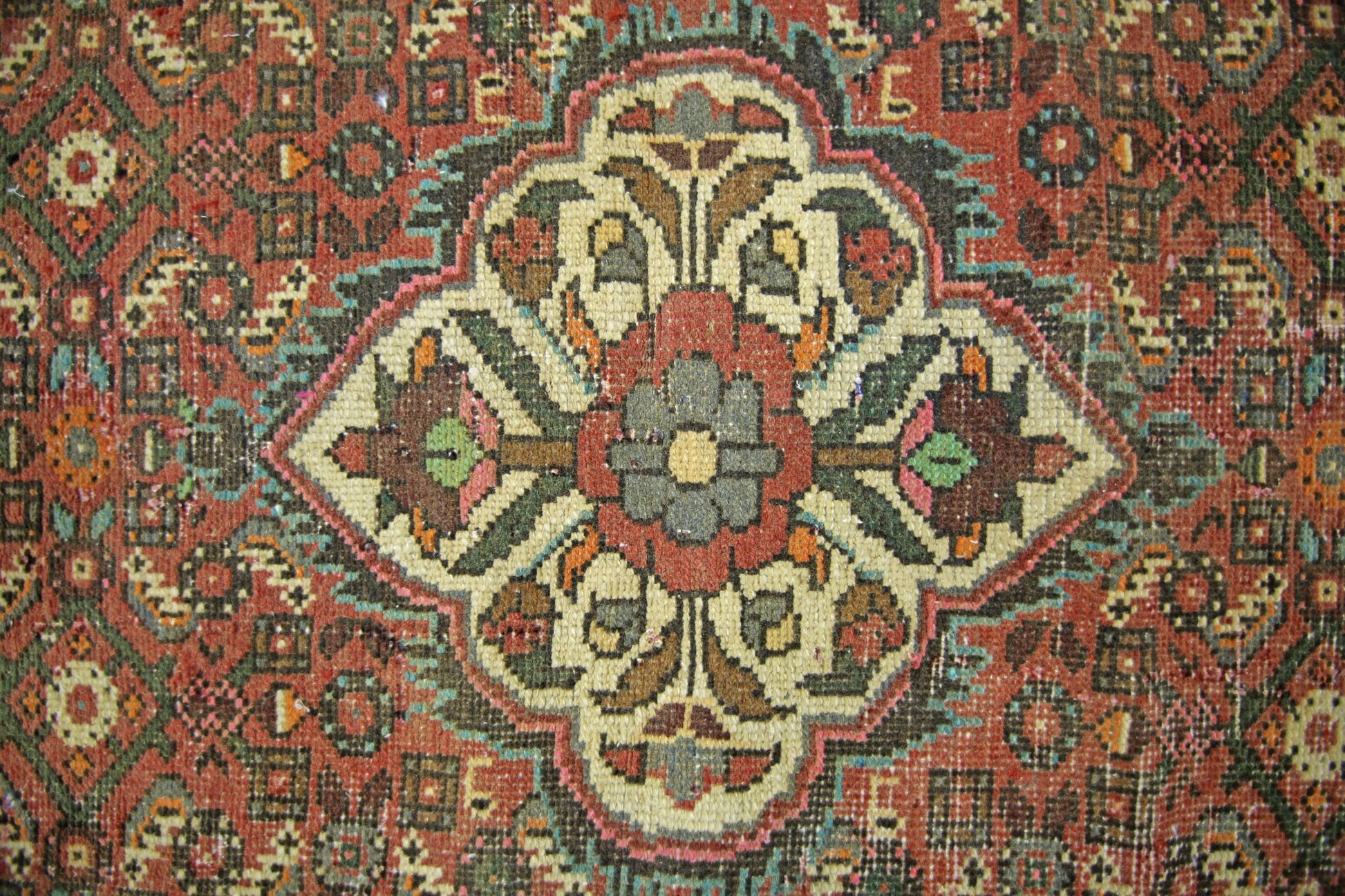 A vintage Persian runner featuring a central floral medallion in a geometric, multi-colored pattern.