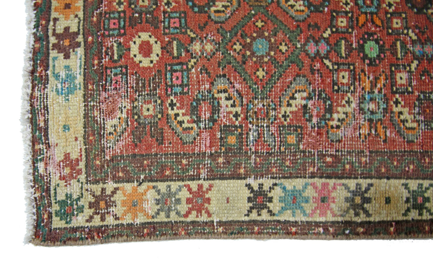 A vintage Persian runner featuring a geometric red field with colorful floral border patterns.
