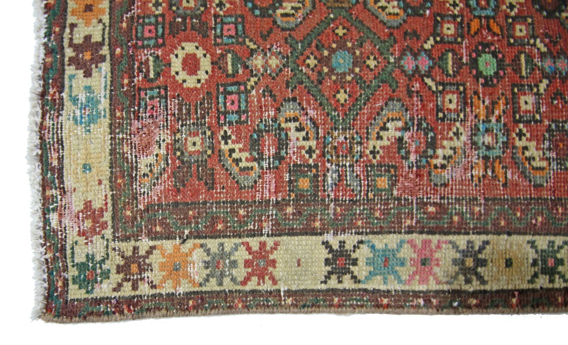 A vintage Persian runner featuring a geometric red field with colorful floral border patterns.