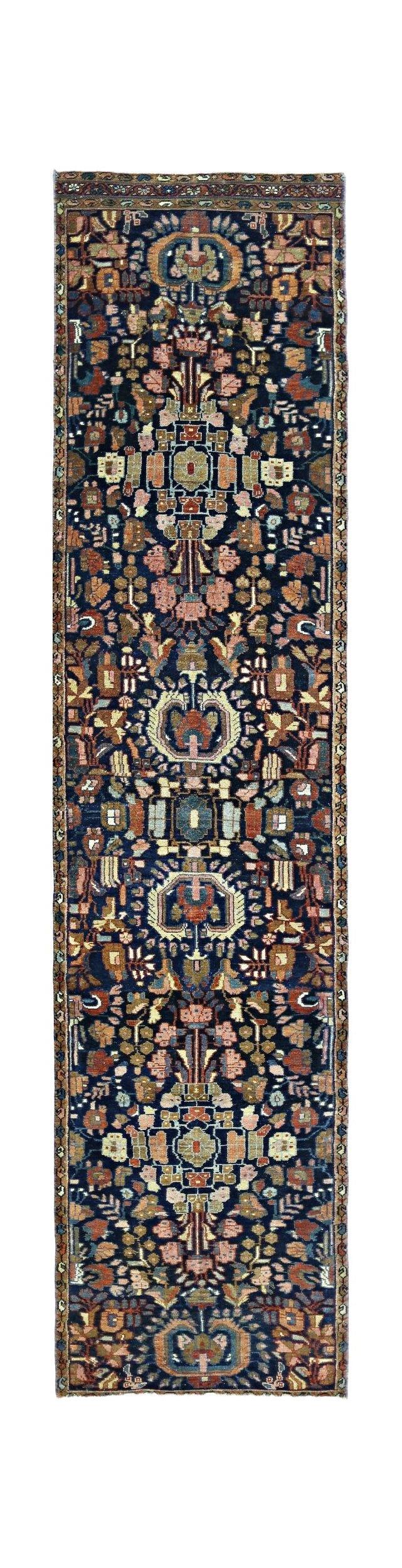 A vintage Persian Malayer runner featuring a floral pattern in muted tones on a dark blue field.