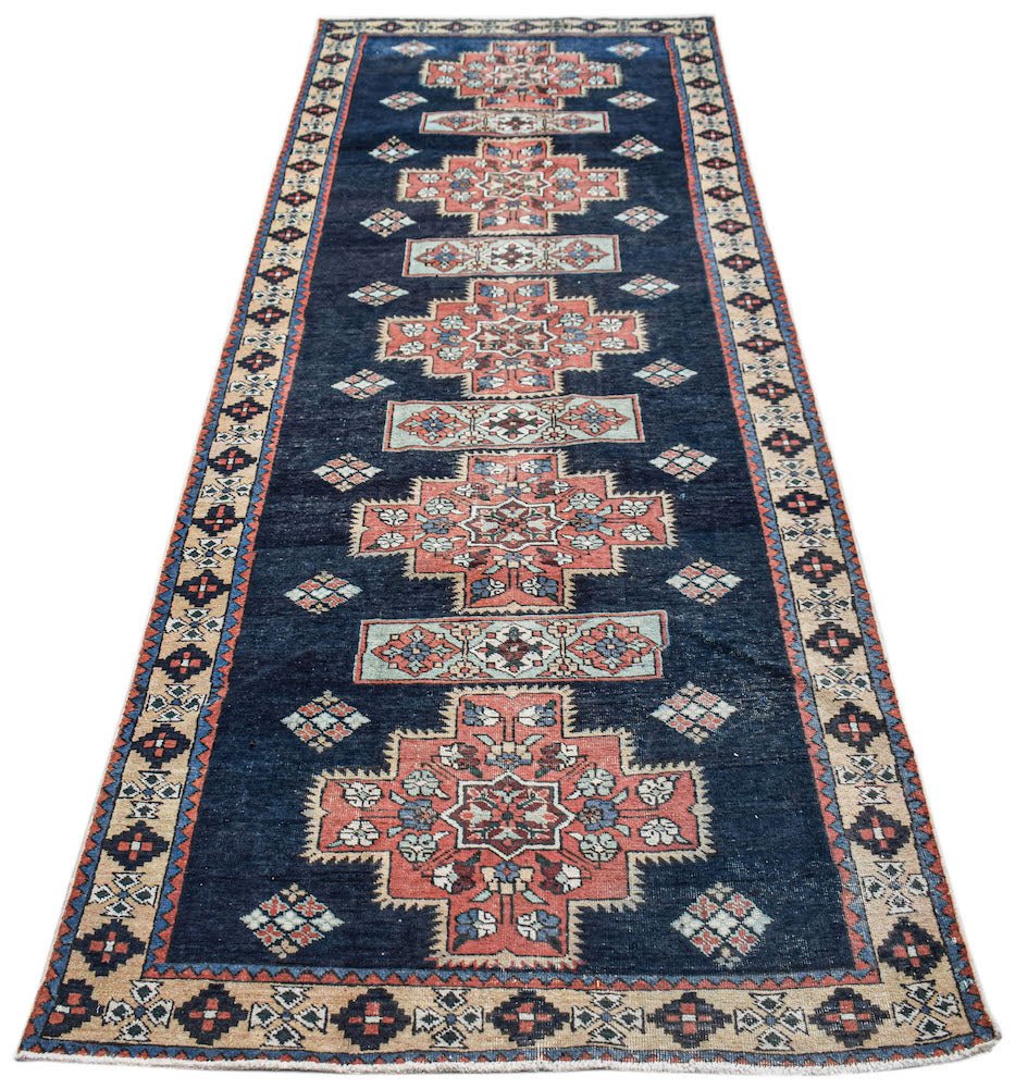 A vintage Persian Ardabil runner featuring geometric floral motifs in red and blue on a dark field.