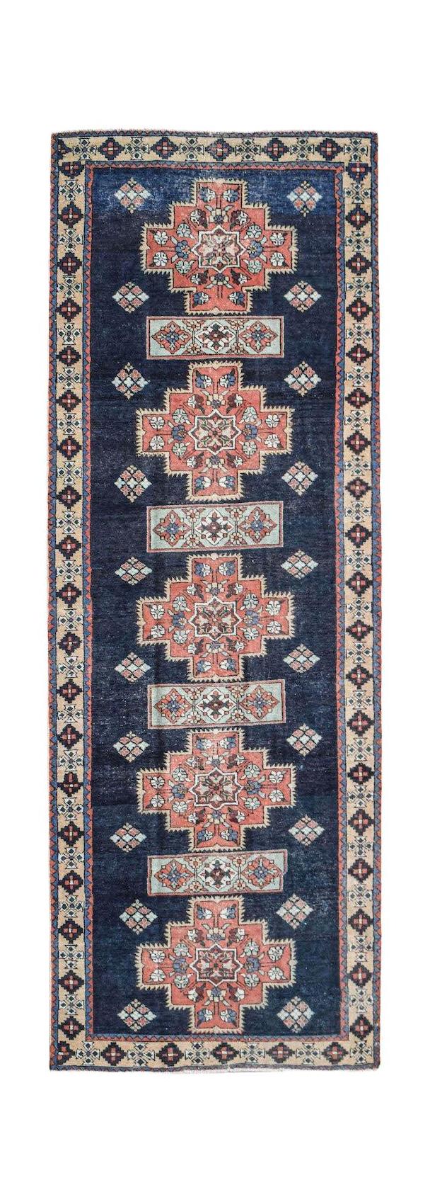 A vintage Persian Ardabil runner featuring geometric medallions on a deep blue wool field.